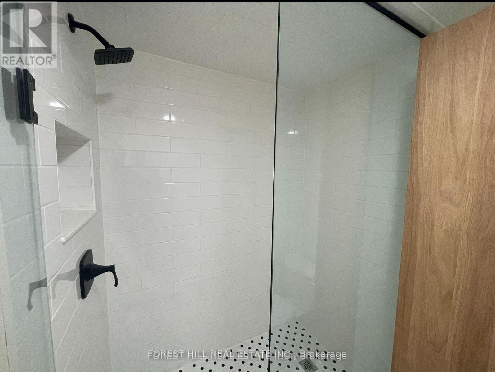 A shower area with a glass door and a wooden door.