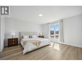 A bedroom with a large bed, two nightstands, and a window overlooking a snowy landscape.