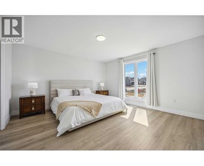 A bedroom with a large bed, two nightstands, and a window overlooking a snowy landscape.