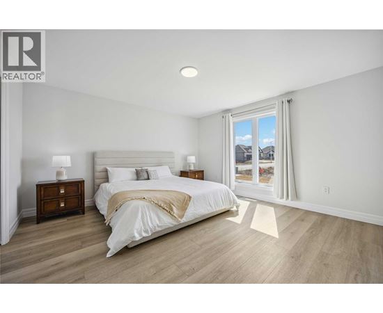 A bedroom with a large bed, two nightstands, and a window overlooking a snowy landscape.