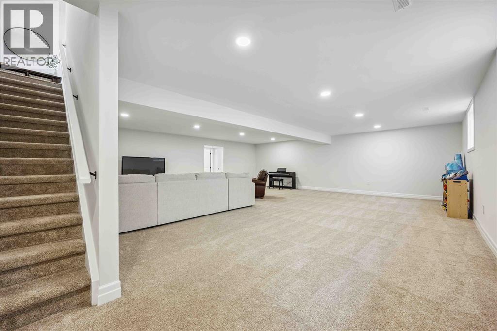 A spacious room with a staircase on the left and a couch in the middle.