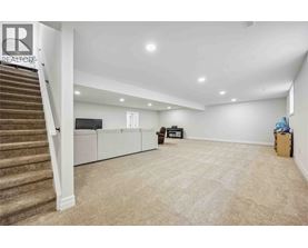 A spacious room with a staircase on the left and a couch in the middle.