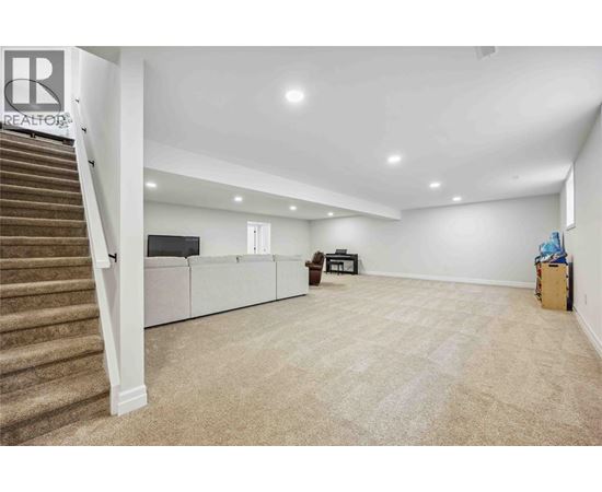 A spacious room with a staircase on the left and a couch in the middle.
