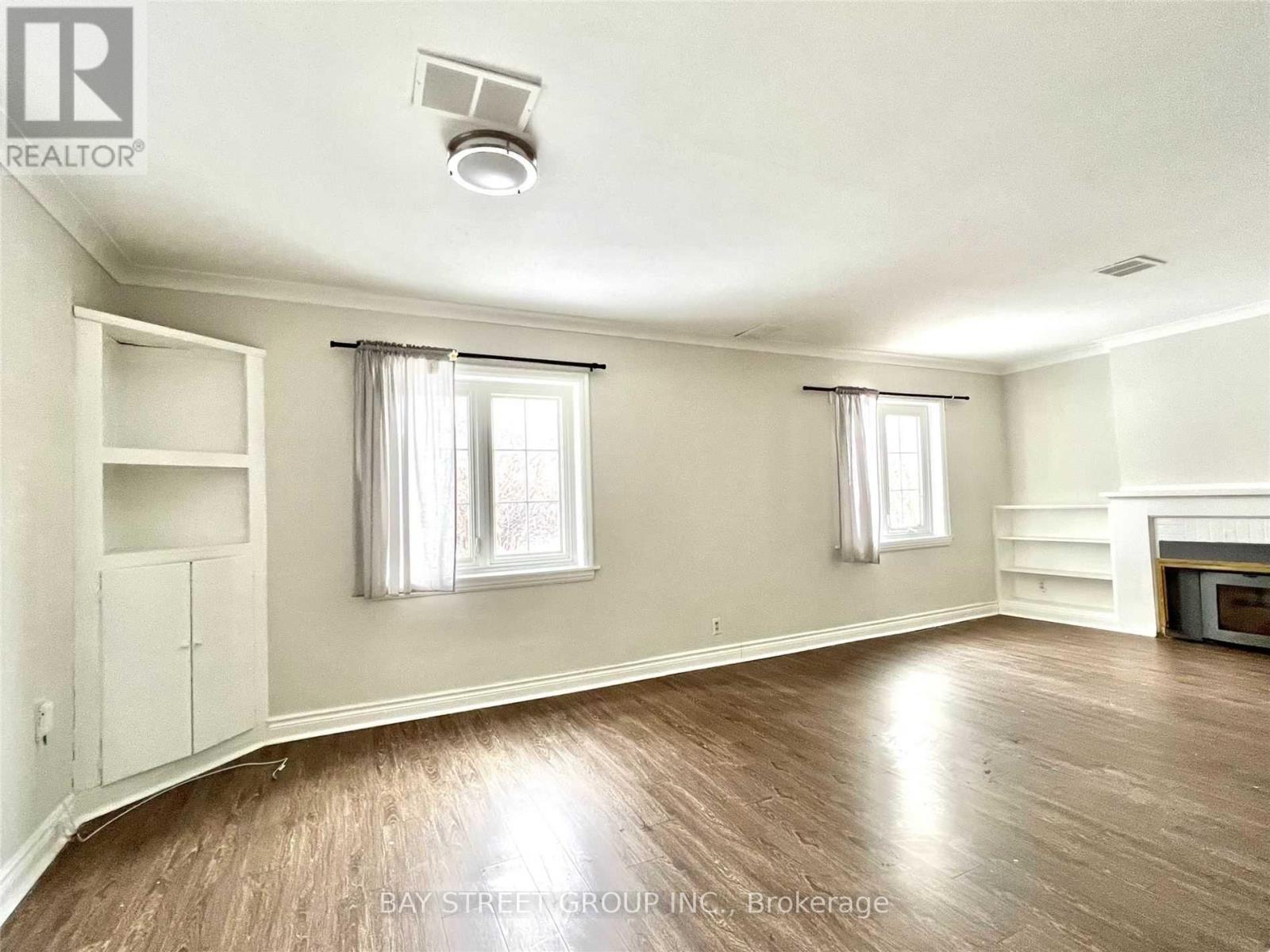 A well-lit, empty room with wooden floors and white walls.