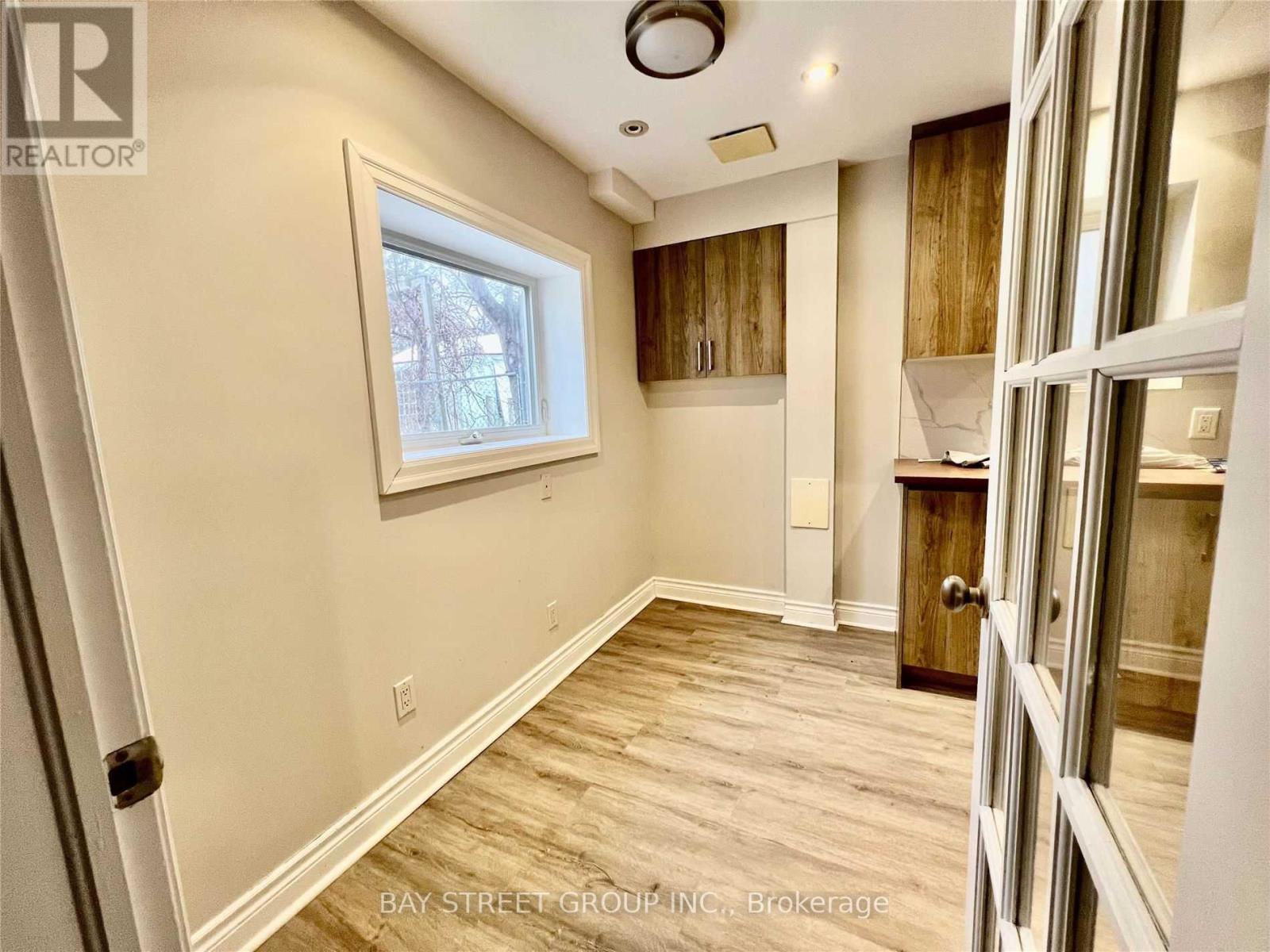 A well-lit room with wooden flooring and a window.