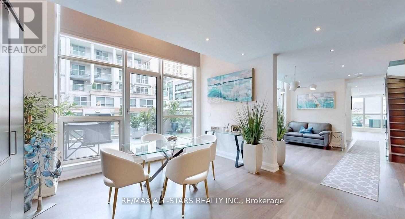 A modern living room with a glass table and chairs, a sofa, and a view of the city.