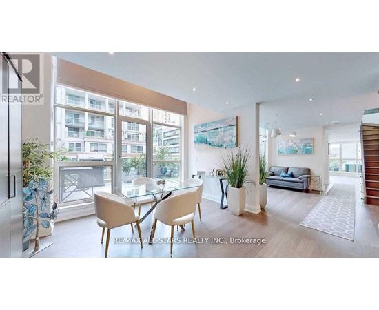 A modern living room with a glass table and chairs, a sofa, and a view of the city.