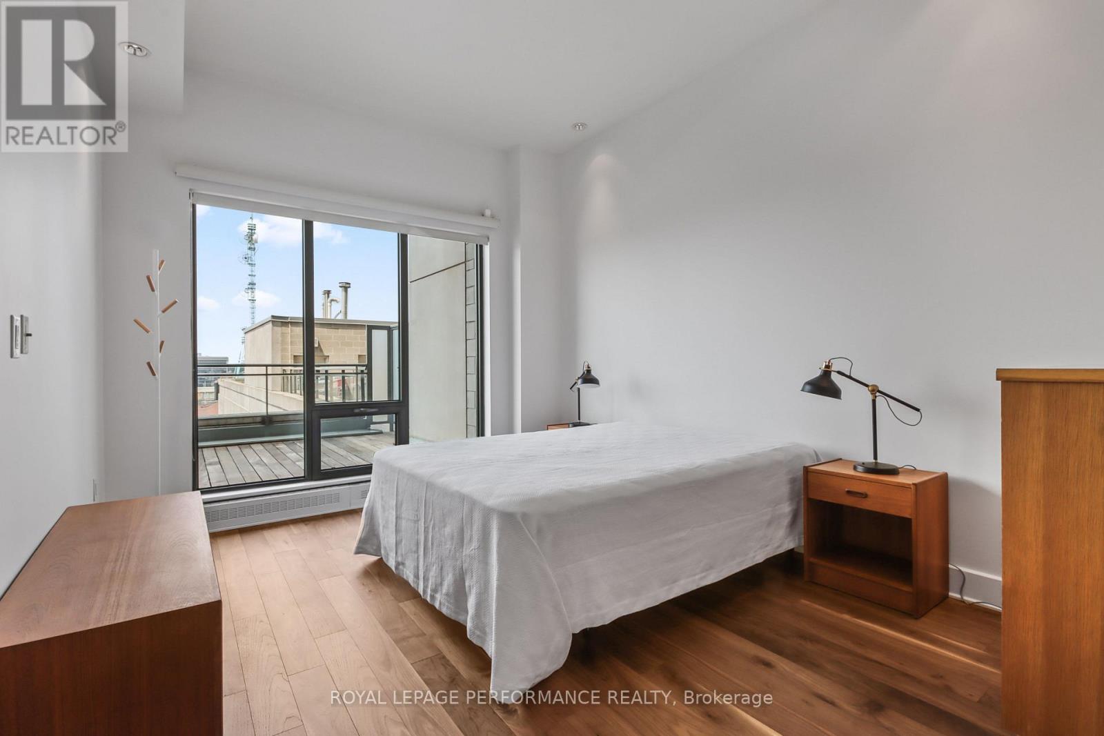 A bedroom with a bed, nightstand, and a window overlooking a balcony.