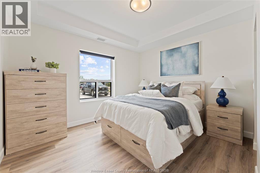 A bedroom with a large bed, a dresser, and a window overlooking a parking lot.