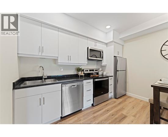 A kitchen with white cabinets and a black countertop.