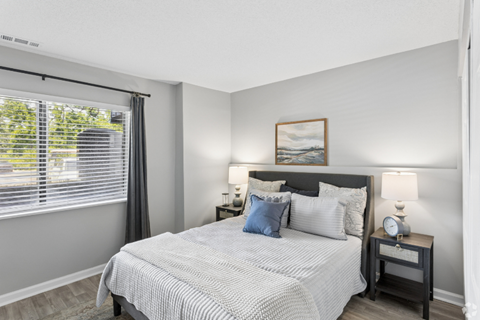 A bedroom with a large bed and a nightstand with a clock.
