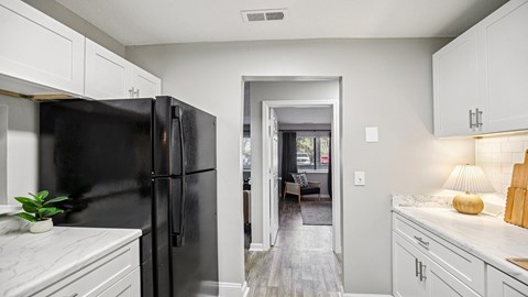 A black refrigerator in a kitchen with white cabinets.