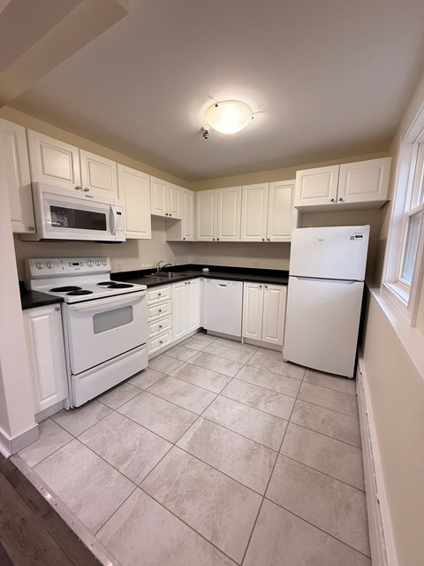 A kitchen with white appliances and cabinets.