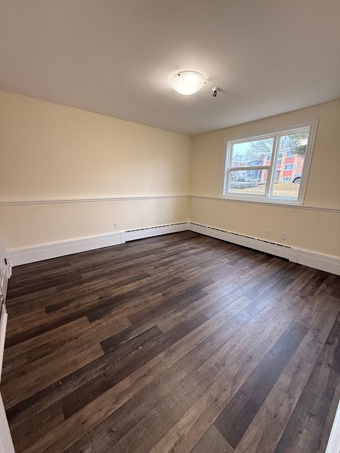 A room with wooden flooring and a window.
