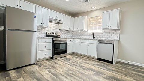 A kitchen with a refrigerator, oven, and dishwasher.