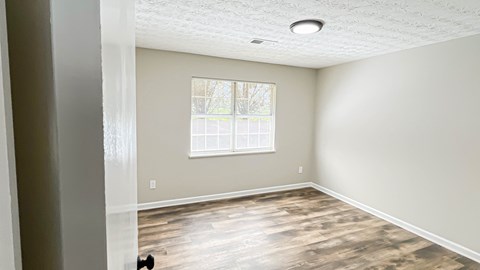 A room with a window and a wooden floor.