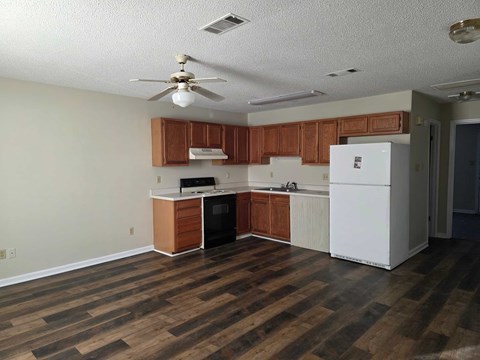 A kitchen with wooden floors and white appliances.