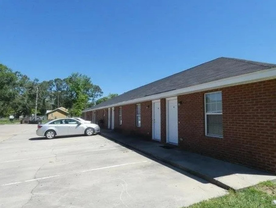 A car is parked in a parking lot in front of a brick building.