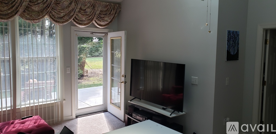 A living room with a television and sliding glass doors.