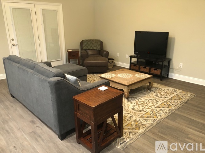 A living room with a grey couch, a brown armchair, a wooden coffee table, and a television on a stand.
