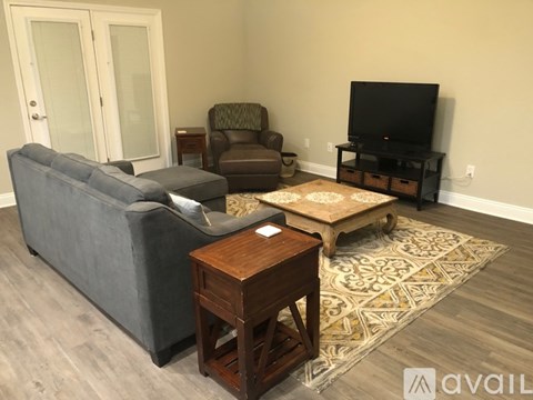 A living room with a grey couch, a brown armchair, a wooden coffee table, and a television on a stand.
