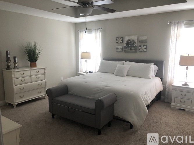 A bedroom with a bed, nightstand, and a dresser with a plant on top.