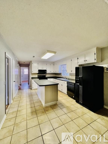 A kitchen with black appliances and white cabinets.
