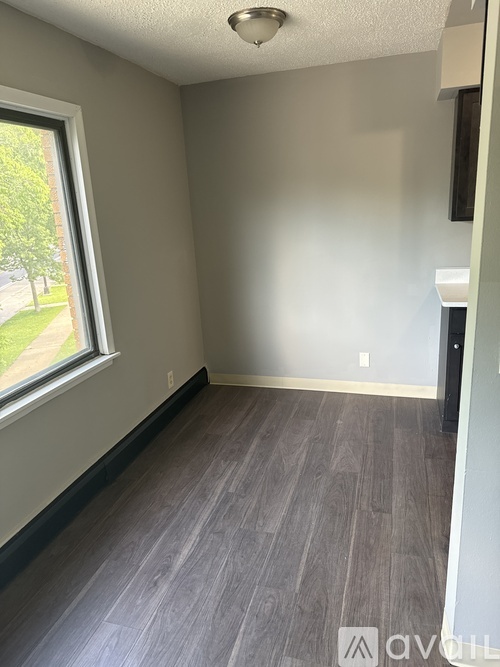 A room with a window and grey flooring.