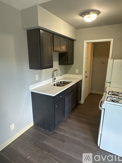 A kitchen with a white sink and black cabinets.