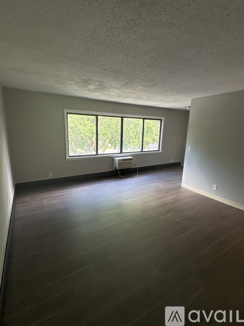 A room with wooden floors and a window letting in natural light.