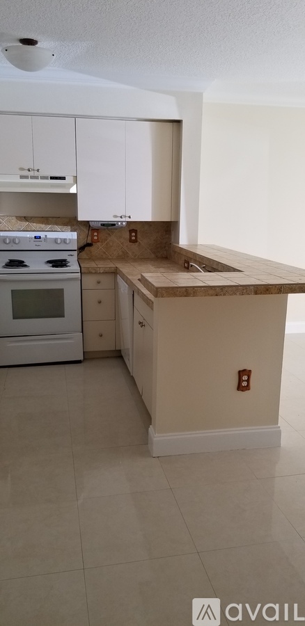 A kitchen with white cabinets and a tiled floor.