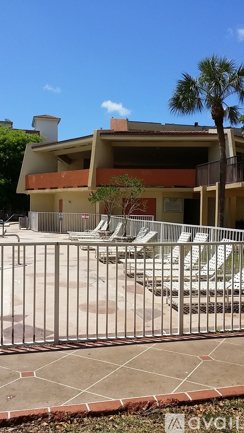 A building with a pool and palm tree in front.