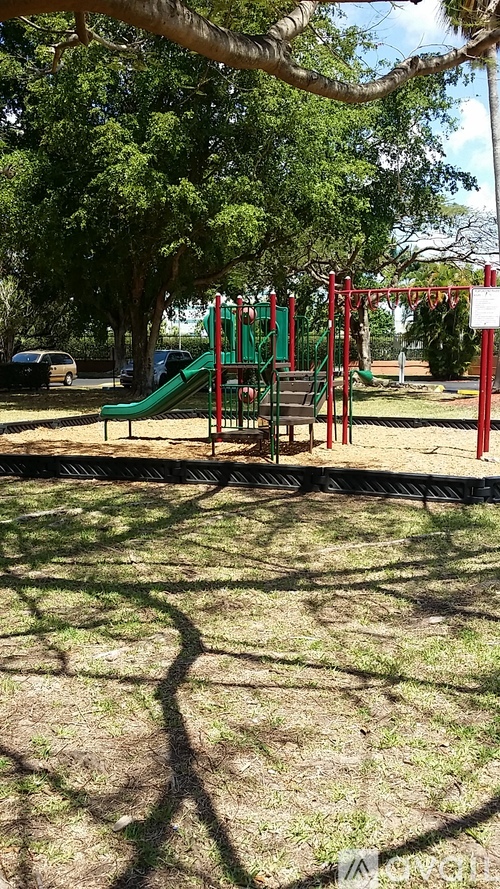A playground with a green slide and red poles.