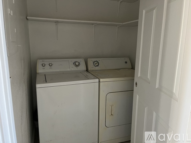 Two white washing machines in a small, white-walled laundry room.