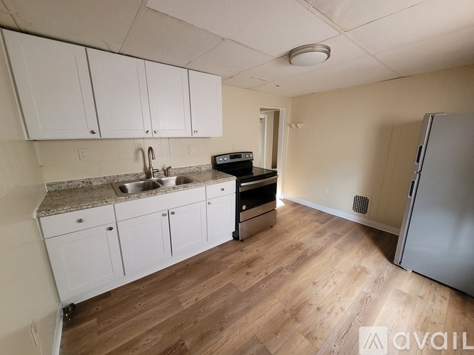 A kitchen with white cabinets and a wooden floor.