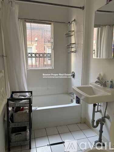 A bathroom with a white sink and a window with a view of a city.