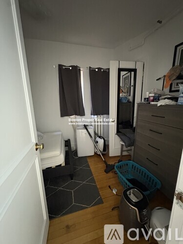A room with a white door, a white toilet, a white cabinet, a white wall, a white floor, a white ceiling, a white window, a white wall with a window, a white wall with a window, a white