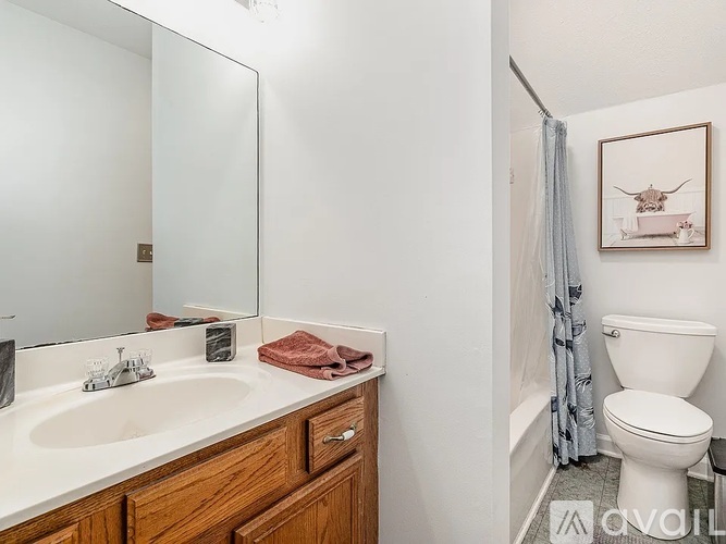 A bathroom with a toilet, sink, and a painting of a longhorn.