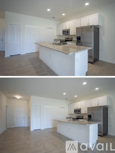 A kitchen with white cabinets and a marble countertop.