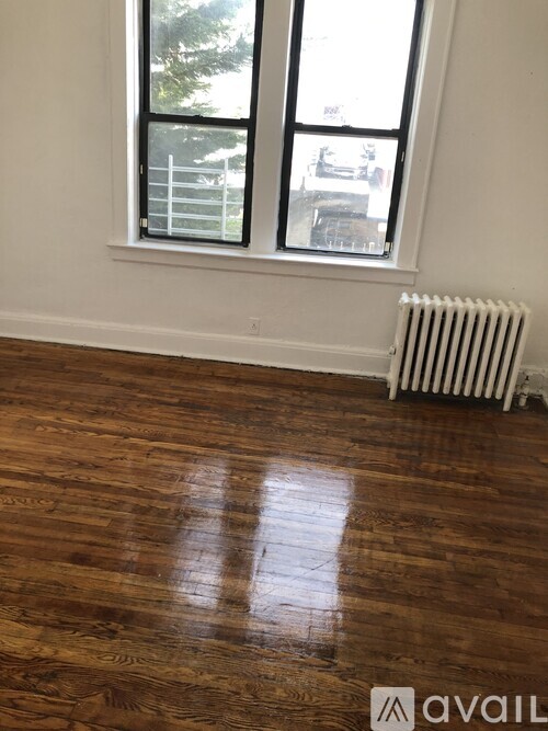 A room with a wooden floor and a window with a white frame.