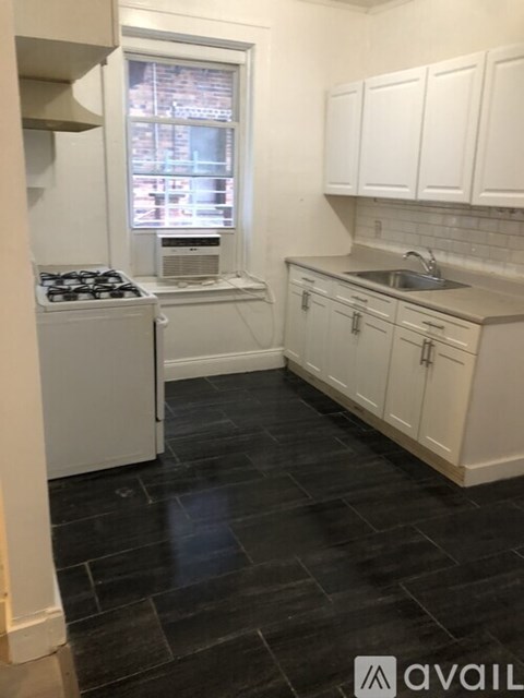 A kitchen with black tile flooring and white appliances and cabinets.