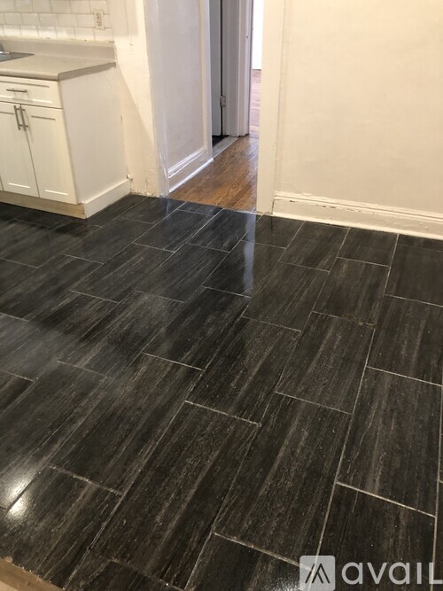 A kitchen with black tile flooring and white cabinets.