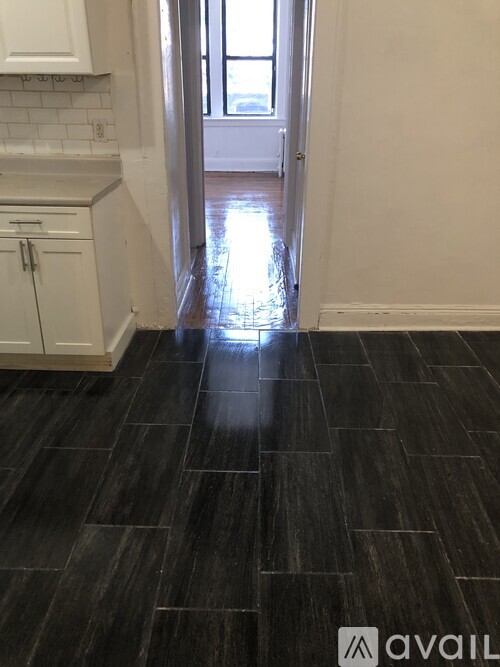 A kitchen with black tile flooring and white cabinets.