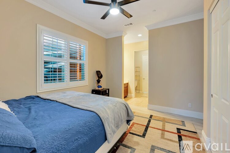 A bedroom with a bed, a ceiling fan, and a window with blinds.