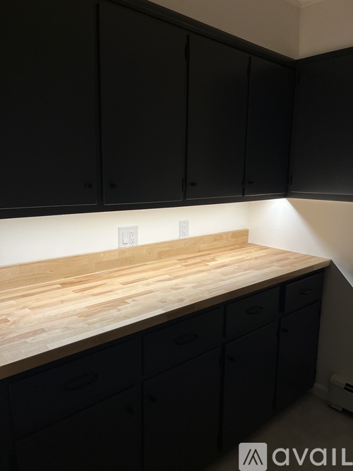 A kitchen with black cabinets and a wooden countertop.