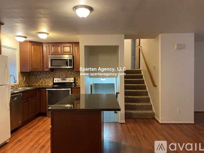 A large empty room with a kitchenette in the Spartan Agency, LLC office.