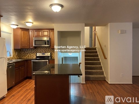 A large empty room with a kitchenette in the Spartan Agency, LLC office.