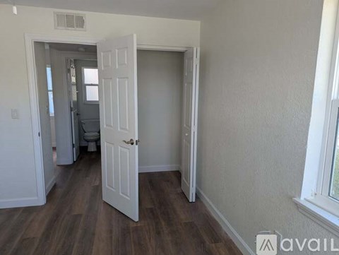 A room with a white door and a window with a view outside.