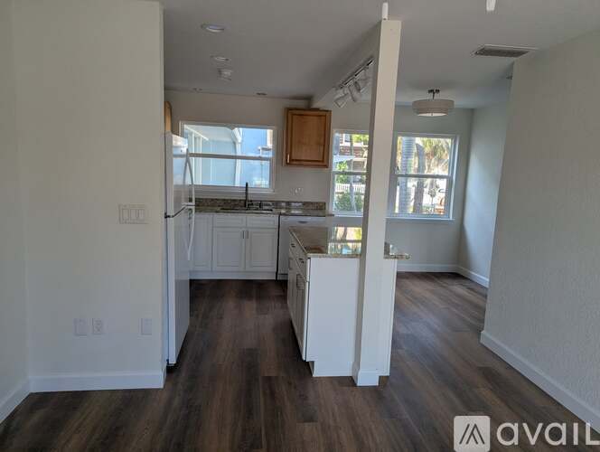 A kitchen with white cabinets and a wooden floor.