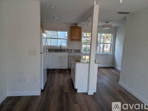 A kitchen with white cabinets and a wooden floor.